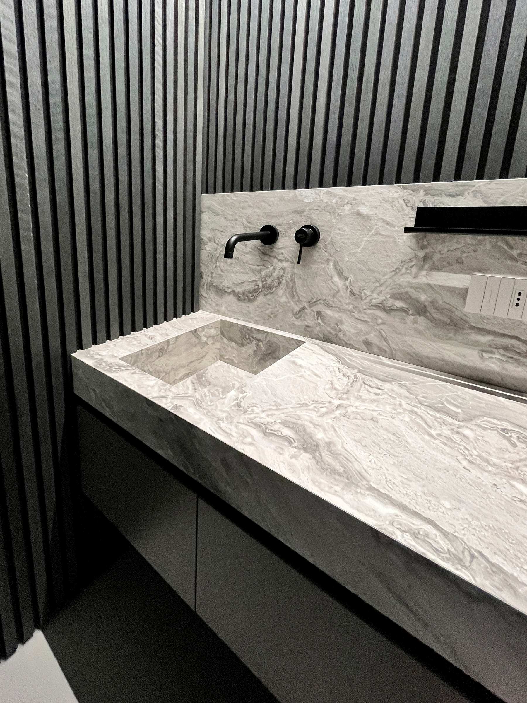 Bagno sartoriale moderno: sistema sospeso in HPL effetto pietra e boiserie grigia — 