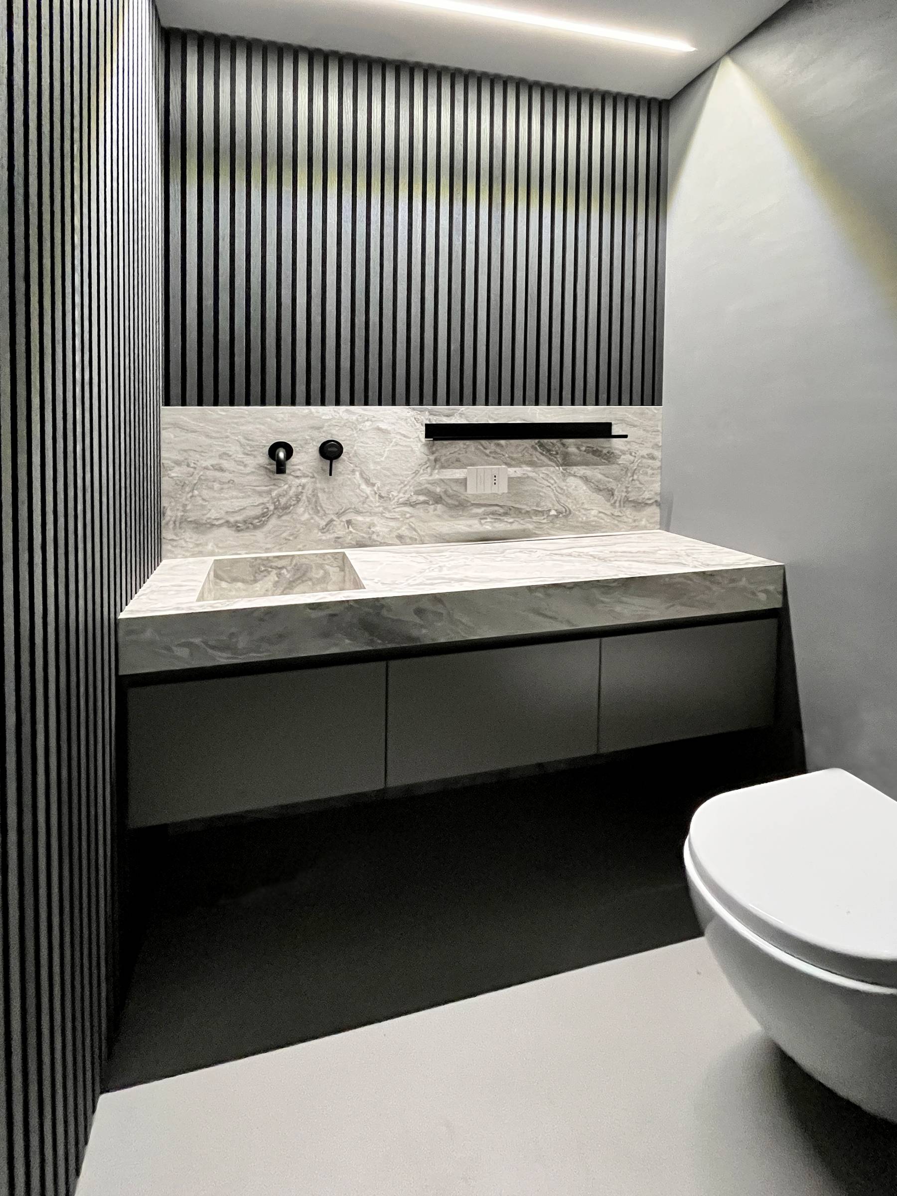 Bergo Arredi — Bagno sartoriale moderno: sistema sospeso in HPL effetto pietra e boiserie grigia