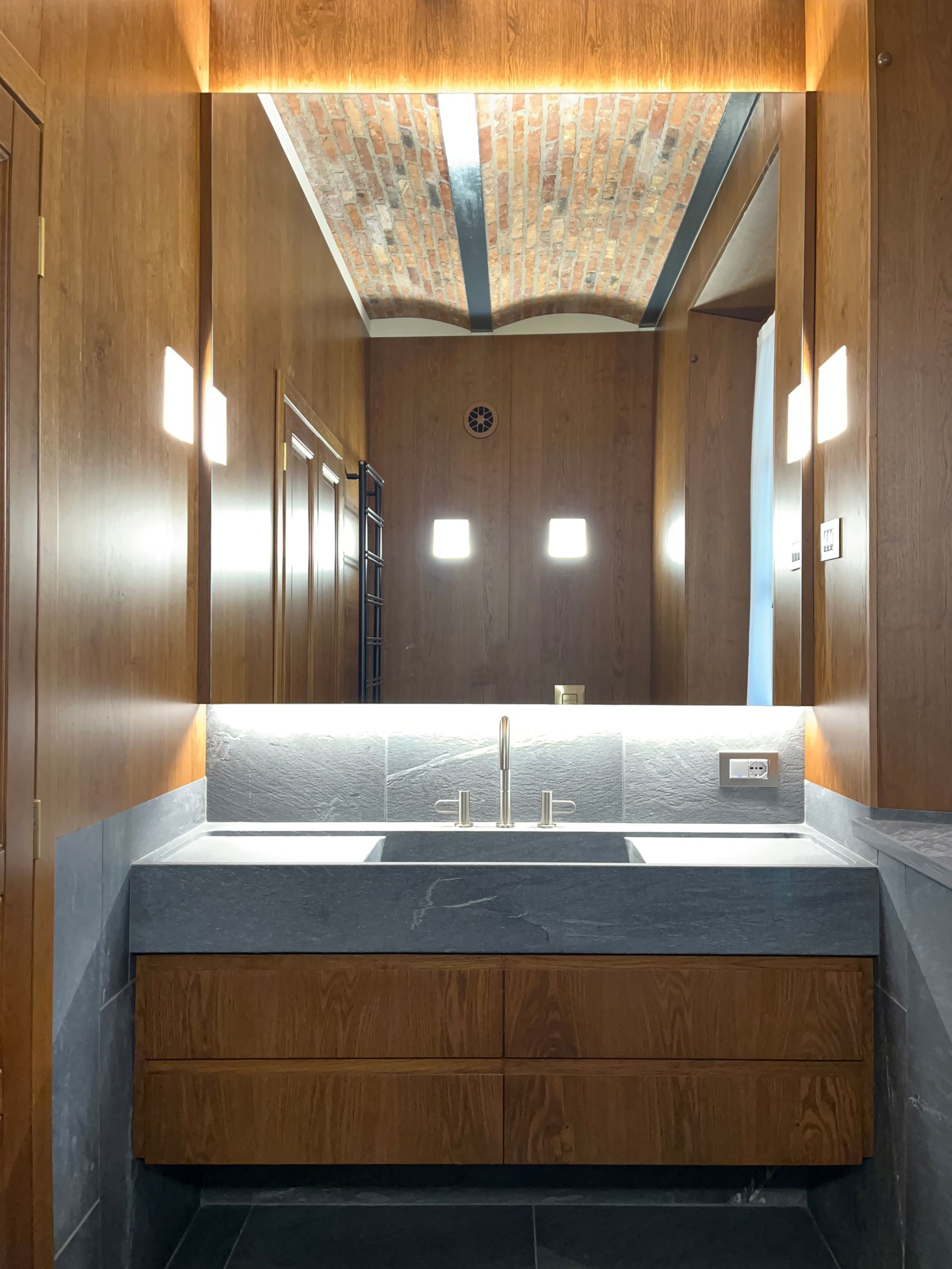 Continuità sartoriale: le sale da bagno su misura coordinate alle porte in massello della residenza. — 
