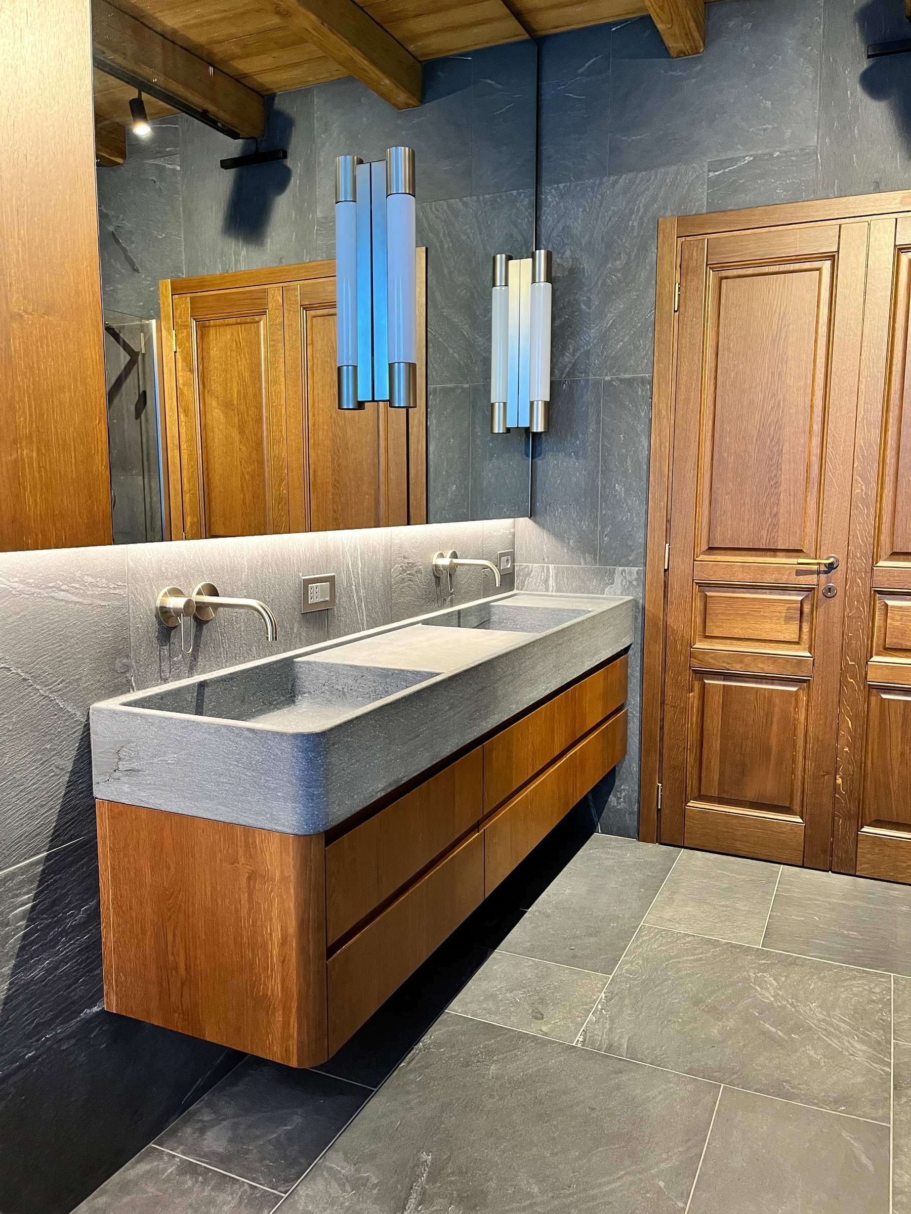 Continuità sartoriale: le sale da bagno su misura coordinate alle porte in massello della residenza. — 