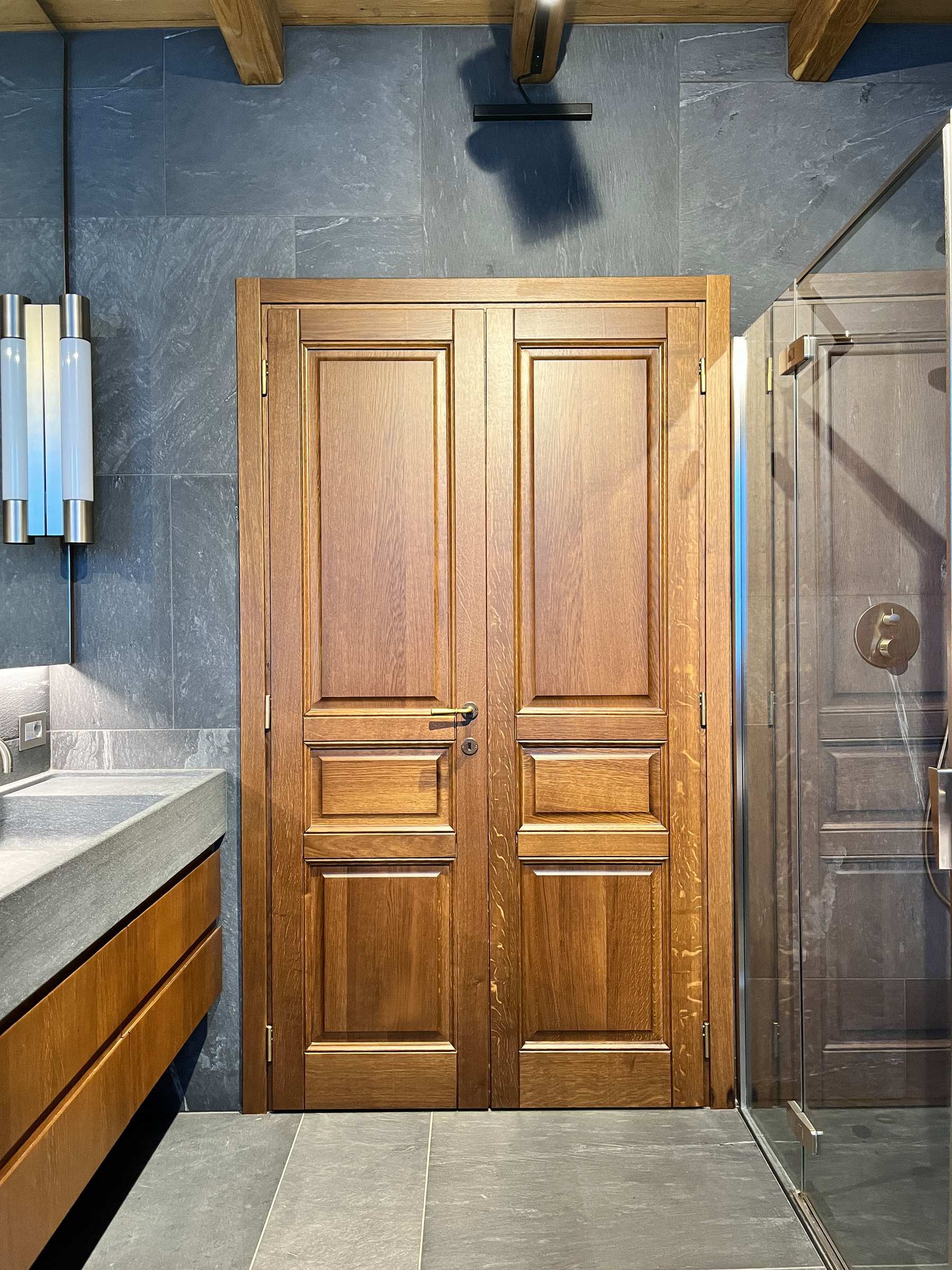 Continuità sartoriale: le sale da bagno su misura coordinate alle porte in massello della residenza. — 