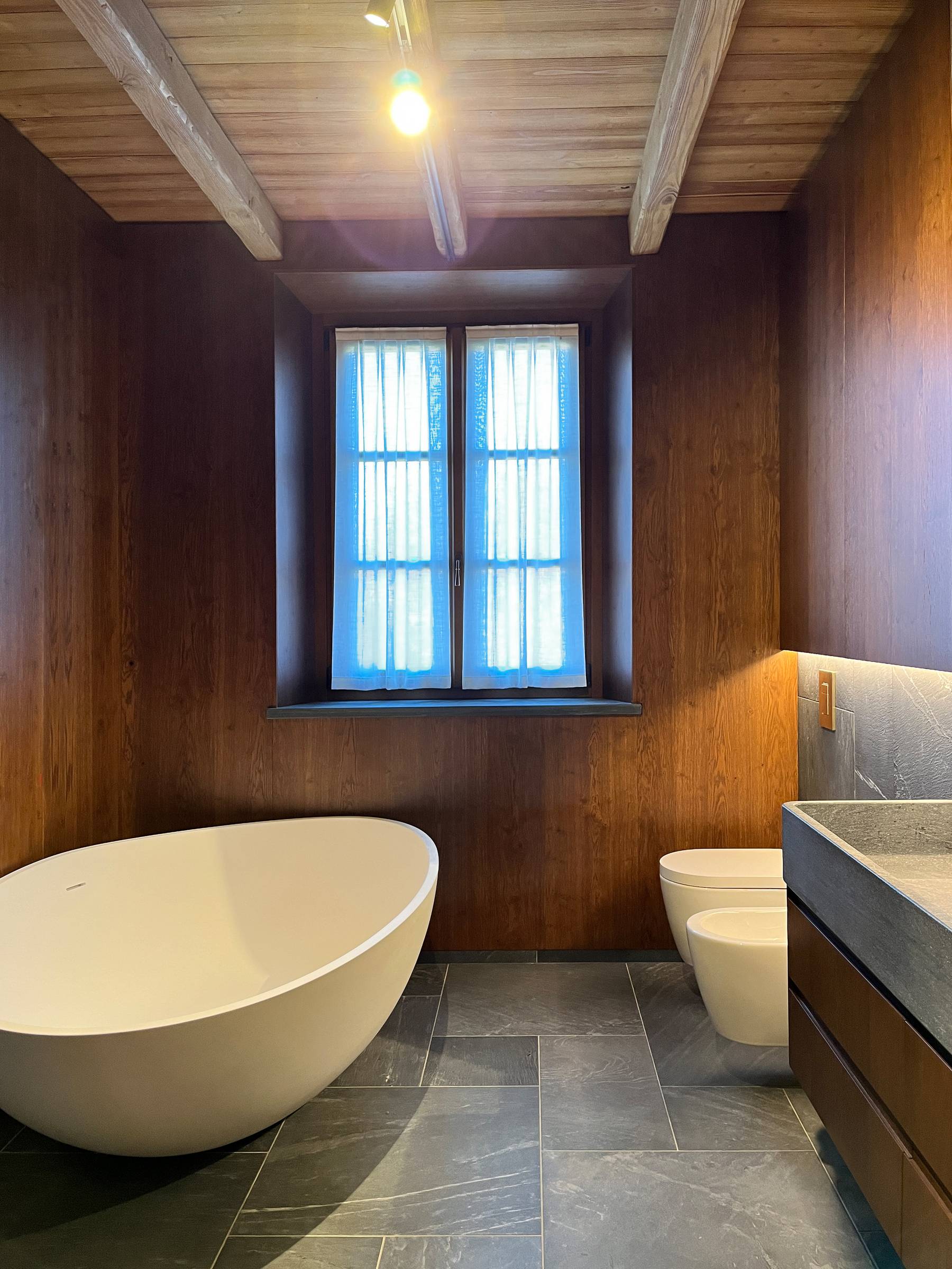 Continuità sartoriale: le sale da bagno su misura coordinate alle porte in massello della residenza. — 
