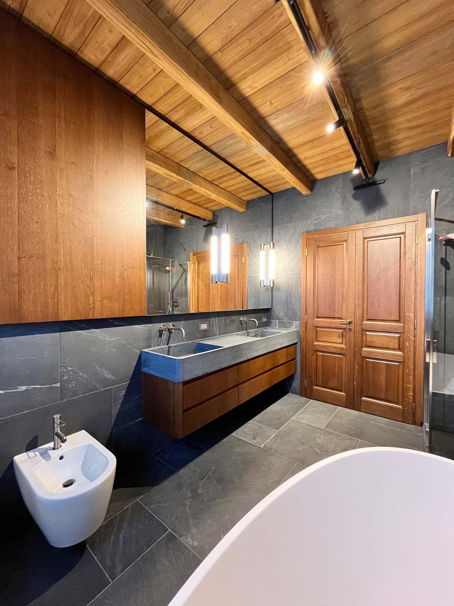 Bergo Arredi — Continuità sartoriale: le sale da bagno su misura coordinate alle porte in massello della residenza.