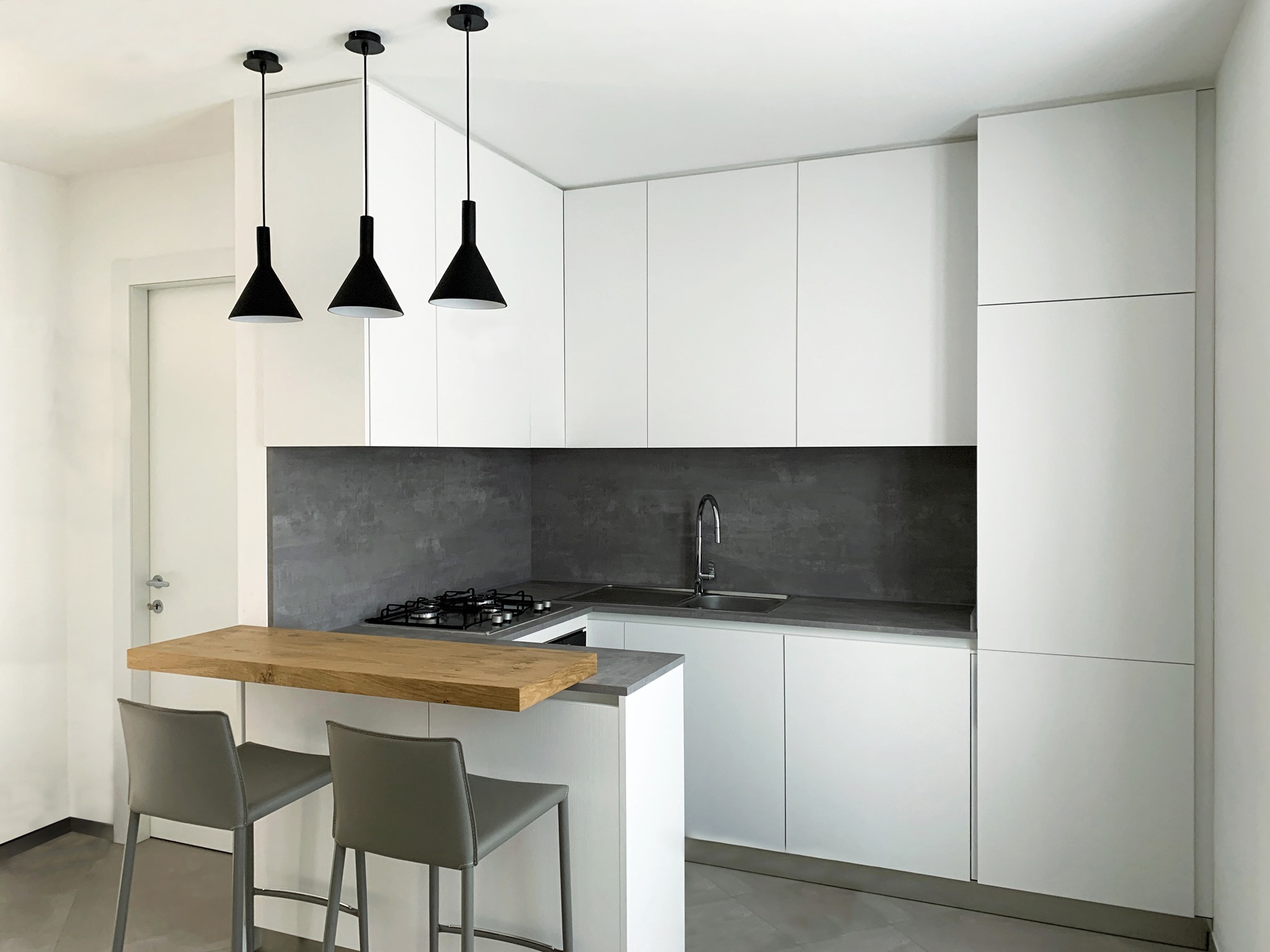 Cucina su misura ad angolo con penisola cemento e bianco: armonia tra design moderno e funzionalità — 