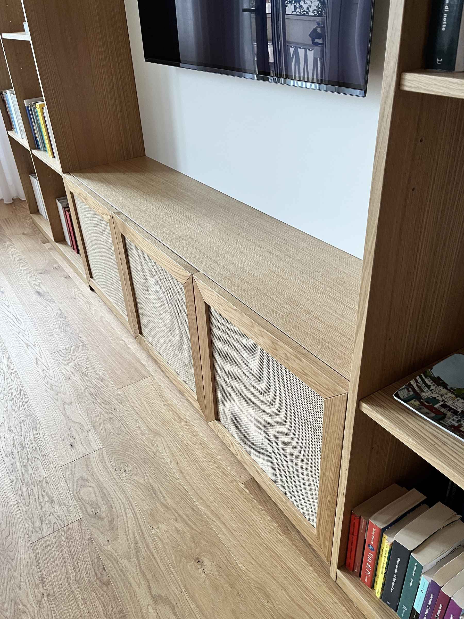 L'arte del dettaglio: la libreria su misura in Rovere Naturale con ante in paglia di Vienna. — 